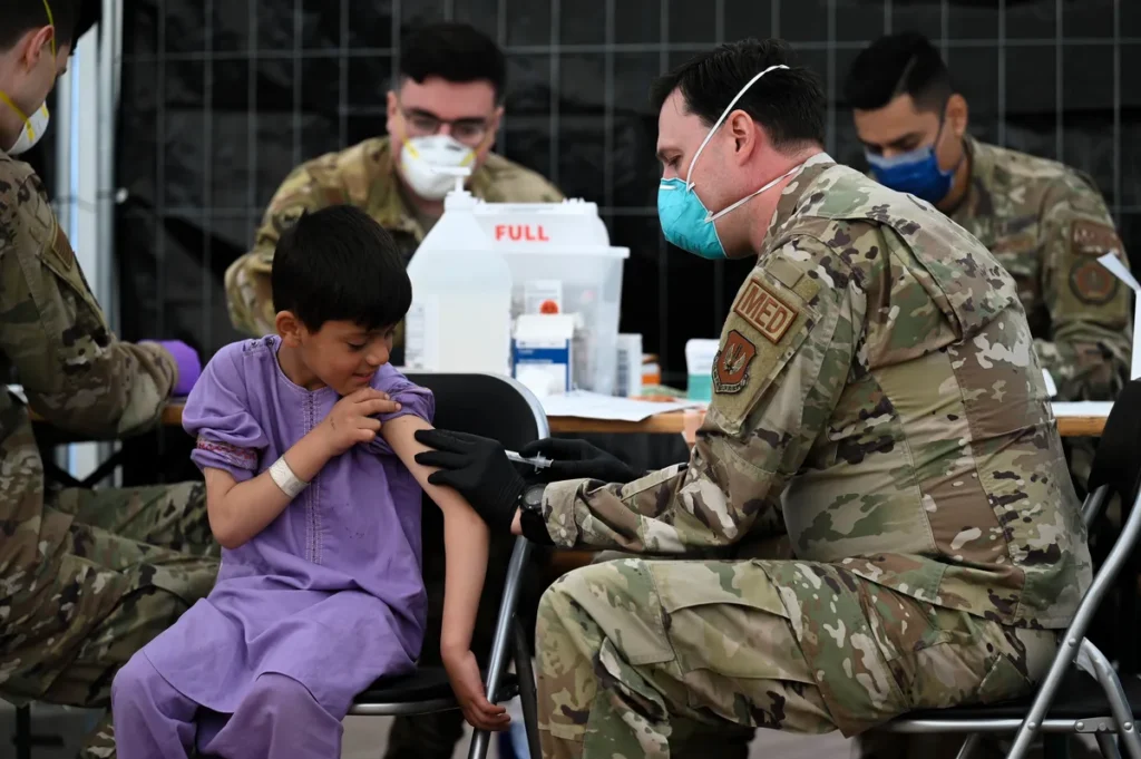 US Air Force medic administering MMR vaccine to a child evacuee at Ramstein Air Base