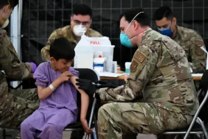 US Air Force medic administering MMR vaccine to a child evacuee at Ramstein Air Base
