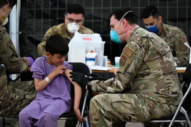 US Air Force medic administering MMR vaccine to a child evacuee at Ramstein Air Base