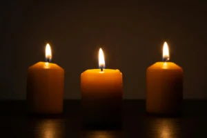 Candles lit in a dark church, casting warm light across empty pews
