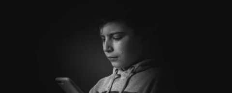 Teenager looking at smartphone screen illustrating adolescent social media harm concerns