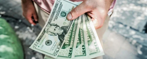 Cash in hand representing UBI pilot programs economic debate
