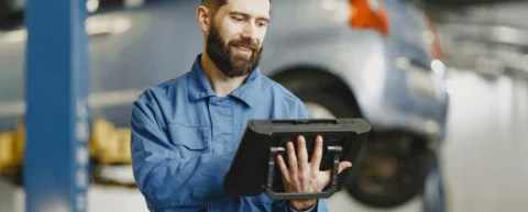 Mechanic using diagnostic tablet to navigate software repair locks on vehicle