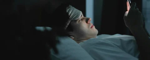 Person in bed exposed to blue light from phone screen illustrating circadian rhythm disruption