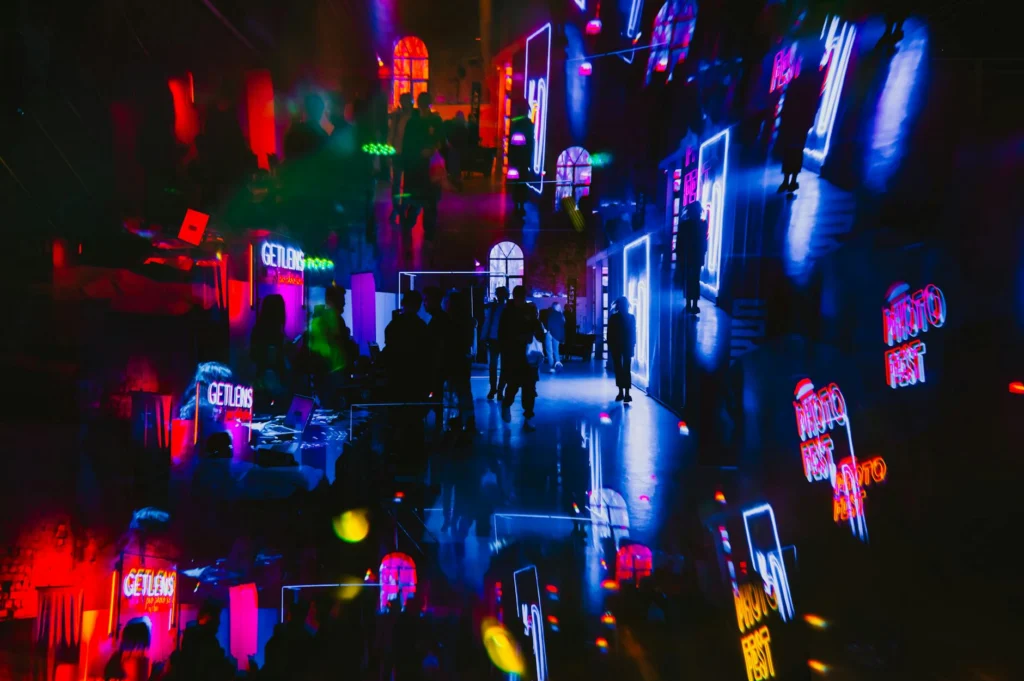 Massive festival crowd illuminated by neon lights, illustrating the scale of the festival-industrial complex