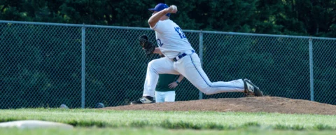 Relief pitcher mid-delivery, illustrating the reliever workload that loads the throwing shoulder