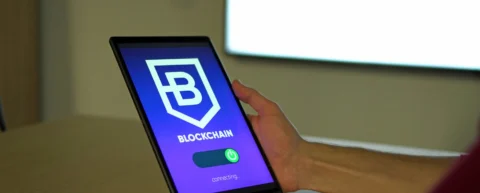 A person holds a tablet displaying a blockchain connection screen.