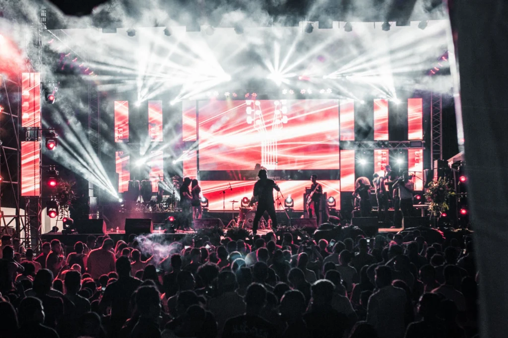 Concert stage lights over a crowd, illustrating the Maluma business model built on music fame