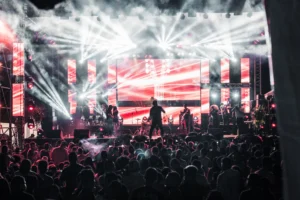 Concert stage lights over a crowd, illustrating the Maluma business model built on music fame