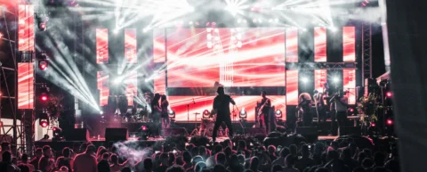 Concert stage lights over a crowd, illustrating the Maluma business model built on music fame